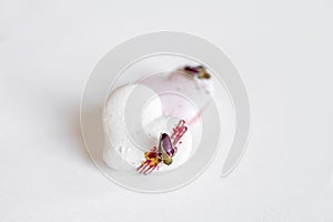 A white heart-shape cake lies on a white plate on a light background. Light macaroons. Delicious pastries