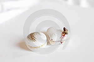 A white heart-shape cake lies on a white plate on a light background. Light macaroons. Delicious pastries