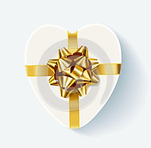White heart shaped gift box with golden bow.