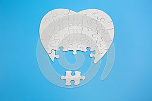 White heart shaped jigsaw puzzle on blue background with copy space. Business strategy teamwork and problem solving concept