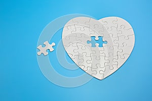 White heart shaped jigsaw puzzle on blue background with copy space. Business strategy teamwork and problem solving concept