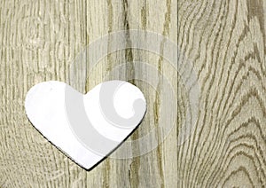 White heart on wooden background.