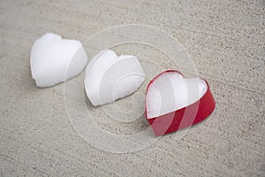 White hearts made of snow with one red colored cookie cutter laying on grey concrete background surface, vintage look