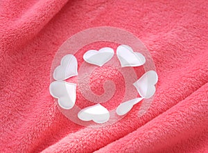 White hearts on pink delicate soft background of plush fabric folds .  St. Valentine`s celebration, romantic concept. copy space