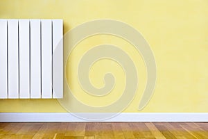 White heater mounted on a yellow wall with wooden floor