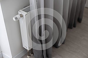 White heater with radiator and a modern thermostat on the wall in an apartment