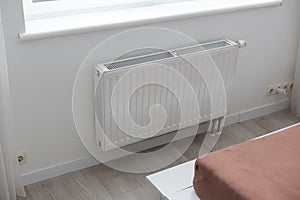 White heater with radiator and a modern thermostat on the wall in an apartment