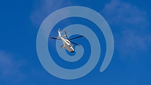 A white helicopter is flying in the sky