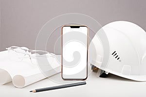 White helmet, smartphone, drawings, plan, pencil on white background, copy space, architectural and construction background