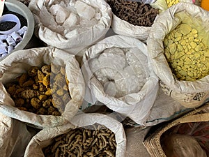 White hessian sacks containing typical Asian spices and root vegetables in food market