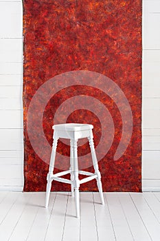 White high wooden stool with a red textured background. Bar chair in white wooden minimalist room. Stool. Bench