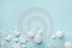 White holiday balls and decorative snowflakes on turquoise pastel background. Christmas or New year border. Minimalistic flat lay