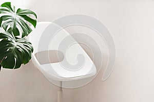 White home armchair empty against light wall, interior of modern apartment house. Cozy corner to relax or work online