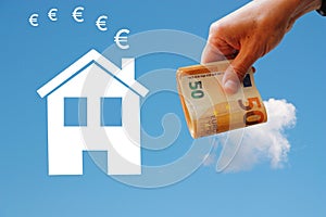 White home on blue background with money in hand