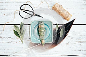 White homemade sage Salvia apiana smudge stick at home with homegrown sage leaves. photo