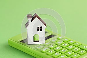 White house, green calculator on green background. Eco concept. Housing Purchase and insurance.