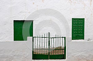 White house with green shutter windows and gate, Spain