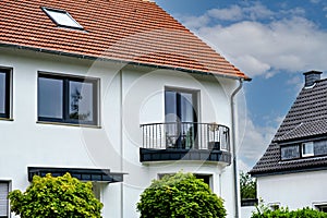 White house with red roof and decorative balcony on the second floor in Germany
