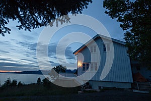 White house on the shore of lake with view to sunset in the Norway at summer