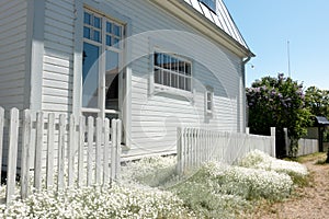 White house with white flower garden by rural dirt road in countryside Swedish village
