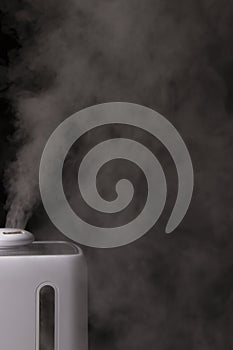White humidifier creates white steam on black background