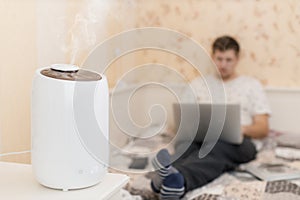 White humidifier spreading steam. Humidification of the dry air in living room.