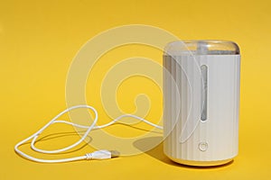 A white humidifier stands on a yellow background.