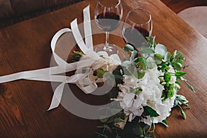 White hydrangea and roses wedding bouquet lying on the wooden table. Eucalyptus and beige ribbon for decoration. Elegant bridal