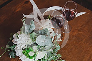 White hydrangea and roses wedding bouquet lying on the wooden table. Eucalyptus and beige ribbon for decoration. Elegant bridal