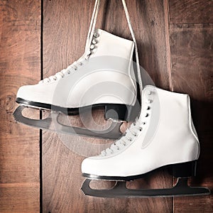 White ice skates for figure skating, hanging on wooden background