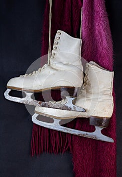 White ice skates hanging with red and pink wool scarf