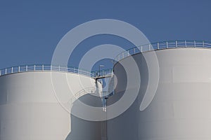 White industrial storage tanks at urban harbor