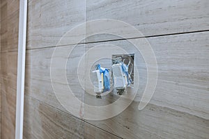 White installation electric switch with connecting wires on bathroom interior light wall