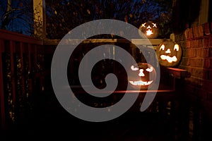 White jack o'lanterns on a bench at night