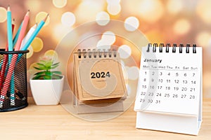 White January 2024 desk calendar on wooden table with gold light bokeh background
