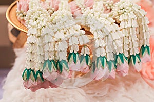 White jasmine garland with pink rose on a gold tray.