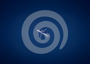 A white jet plane is soaring through a deep blue sky