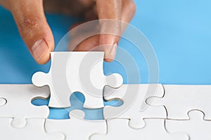 White jigsaw in the hands of humans, The correct solution. Teamwork, Solving and completing the task. Last piece of jigsaw puzzle