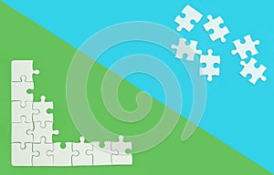 White jigsaw of puzzle on blue and green background.