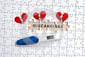 White jigsaw puzzle with miscarriage word over orange background.