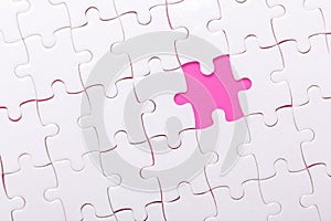 White jigsaw puzzle with with one piece missing and pink background