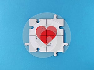 White jigsaw puzzle pieces forming a red heart on blue background