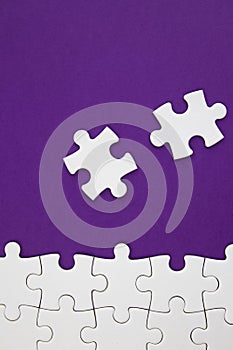 White jigsaw puzzle pieces on purple background with negative space