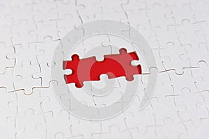 White jigsaw puzzle with two missing pieces on red. Blank missing puzzle for your creative text idea. Blank white and red jigsaw