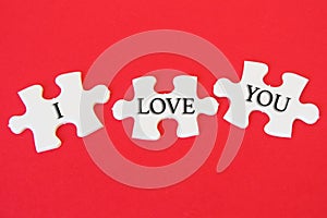 White jigsaw puzzle with a written word I Love You on a red background