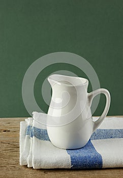 White jug and dishcloth on old wooden table