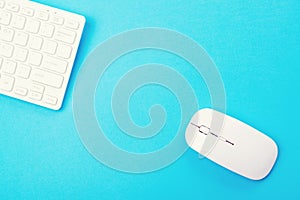 White keyboard and mouse on blue background, top view