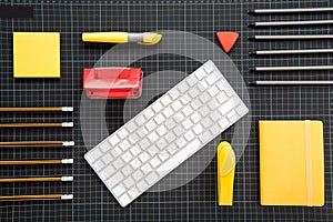 White keyboard and organized office supplies on black