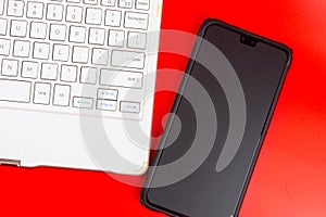 White keyboard with smartphone isolated on red background.
