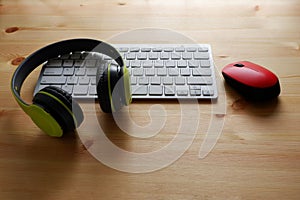 White keyboard with wireless mouse and bluetooth wireless headphones on wooden background.Top view. Computer equipment accessories